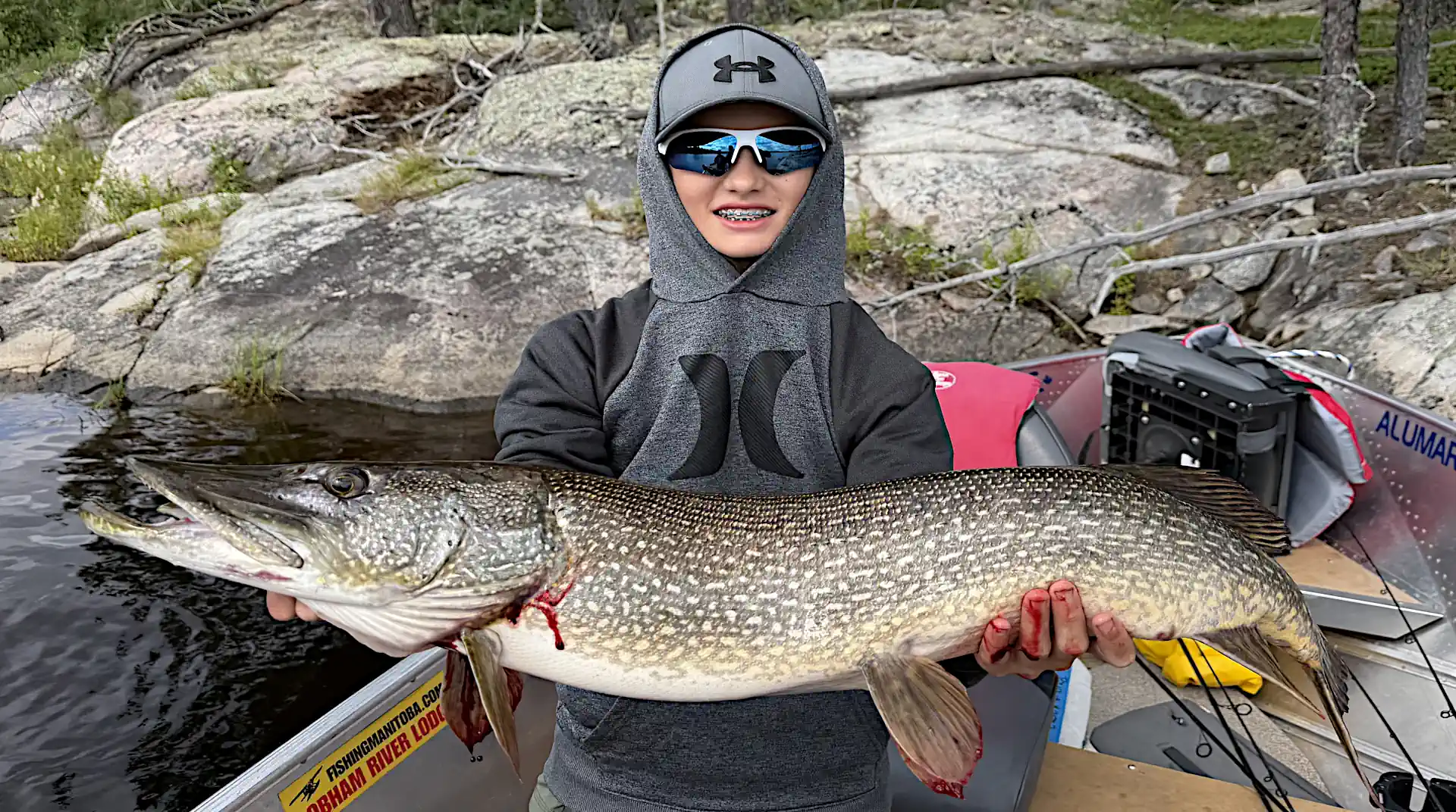 Young angler holding a 40-inch trophy northern pike caught on the Cobham River in Manitoba during late summer