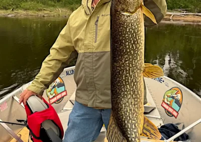 Angler holding a very dark, beautifully patterned trophy Northern Pike in Manitoba, Canada.