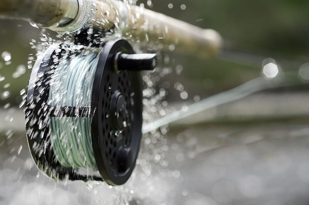Close-up of fishing gear essentials, including rod and reel for fly-fishing.